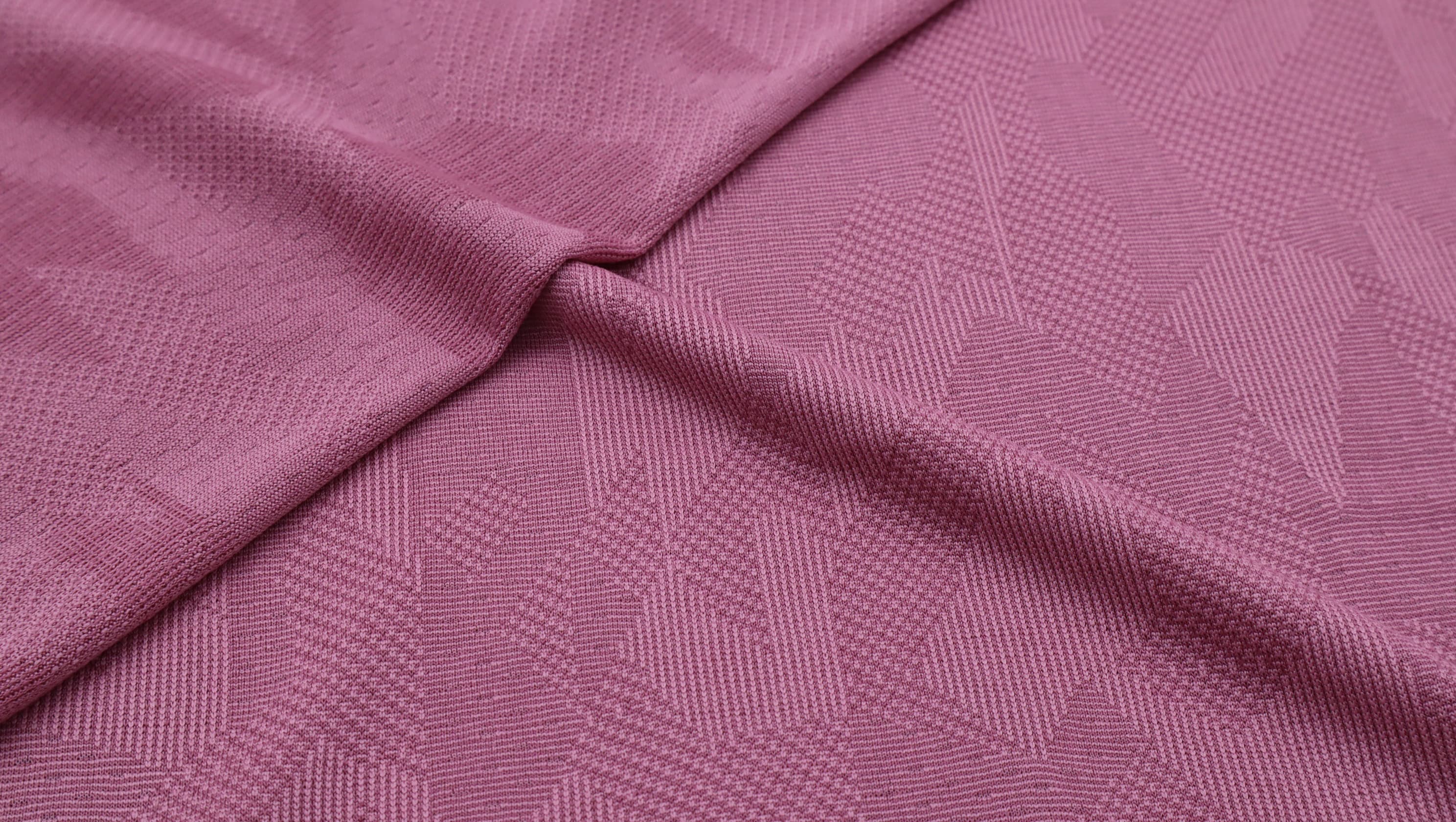 Pink multi-structure jacquard textile showing performance fabric texture.